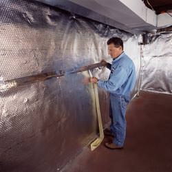 Installation of a radiant heat and vapor barrier on a basement wall in Albion