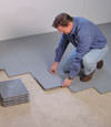 Contractors installing basement subfloor tiles and matting on a concrete basement floor in Edinboro, Pennsylvania