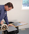 installing a waterproof vapor barrier on a basement floor to prepare for basement carpeting in a Warren home